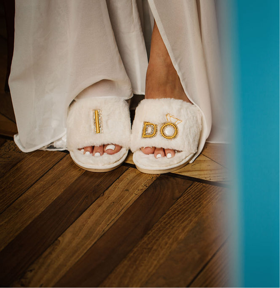 White bridal slippers embroidered with “I DO” in gold