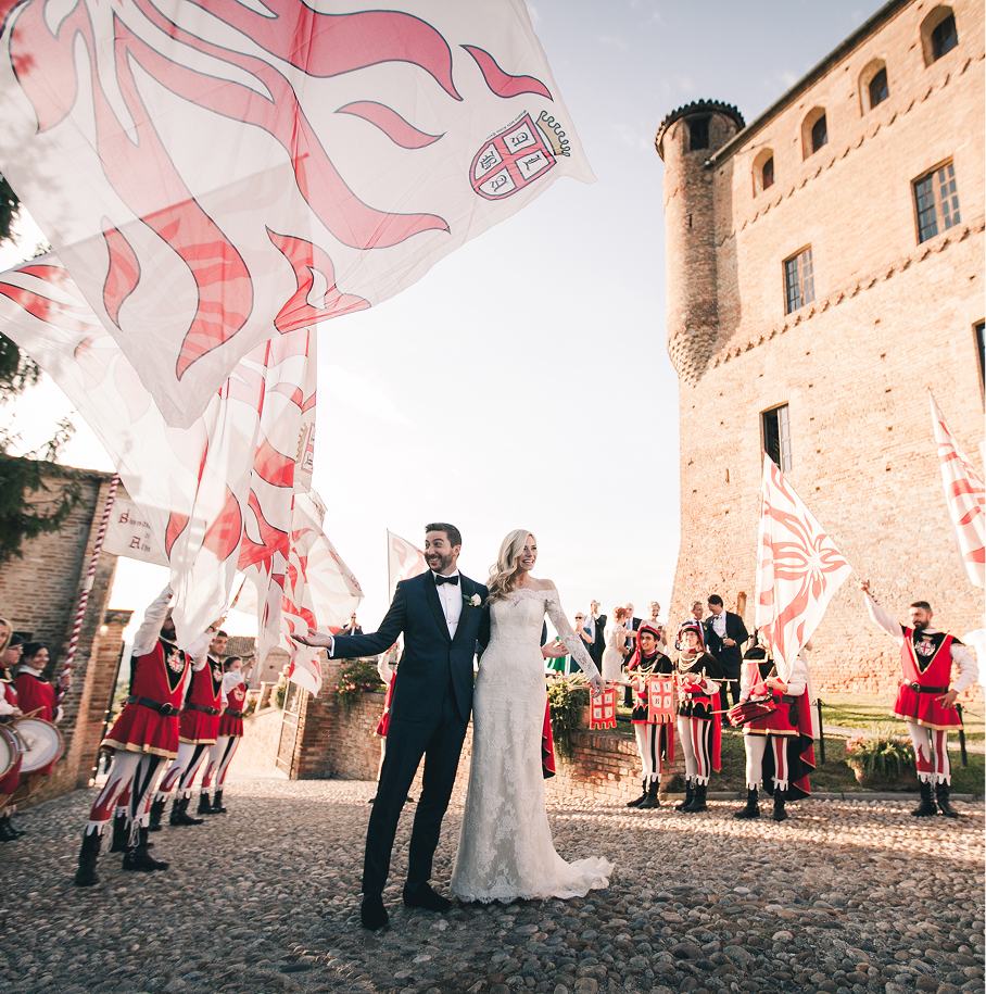 Newlyweds surrounded by flag wavers in front of a castle